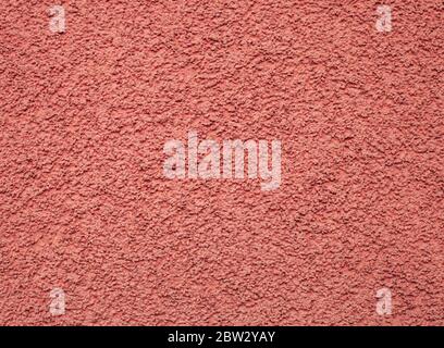 Texture pink pebble dash stucco on facade. House wall red grainy finishing plaster exterior pattern. Abstract rough background vivid color Stock Photo