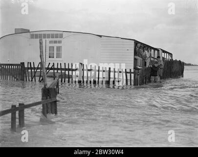 Sea defences broken by flood tide at Winchelsea , bungalows flooded and holidaymakers marooned . The sea defences for a distance of 75 yards along the coast at Winchelsea , Sussex gave way before a flood tide , and a surging torrent of sea water flooded acres of marsh land along the coast , inundating bungalows and marooning holidaymakers . Great efforts are being made to repair the breach before the next tide . 4 September 1932 Stock Photo