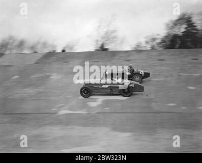 A close race at Brooklands . Crowds thronged the Brooklands track for the great Easter Monday opening meeting when Sir Malcolm Campbell took out his Bluebird on the track . Mr C Penn Hughes in his Bugatti and Mr E L Bouts in his Sunbeam ( nearest camera ) racing nexk and neck round the track in the Norfolk lightning short handicap race . . 28 March 1932 Stock Photo