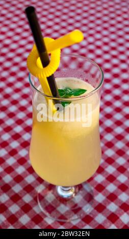 A glass of lemonade on a checkered red-and-white tablecloth. Stock Photo