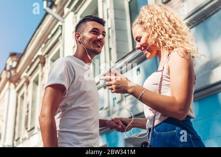 Mixed race couple in love listening to the music on phone and dancing on city street using earphones. Stock Photo