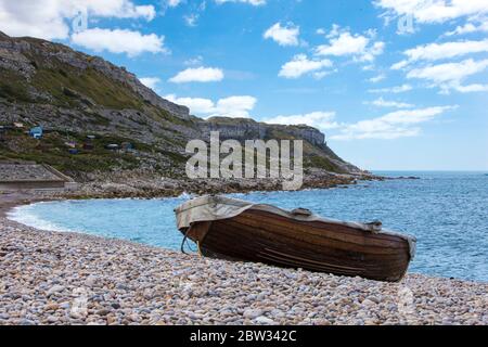 Beautiful sunny morning with a rowing boat beached on Chesil beach near Weymouth in Dorset with Portland in the background Stock Photo