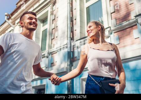 Mixed race couple in love walking and talking on city street. Happy couple hanging and having fun outdoors holding hands Stock Photo