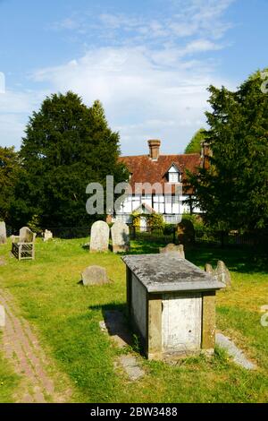 Quaint traditional white timber framed house and gravestones in churchyard of parish church, Speldhurst, Kent, England Stock Photo