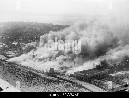 Million dollar fire destroys famous Coney Island pleasure resort . New York ' s famous pleasure beach Coney Island was swept by a disastrous fire which destroyed it . Hundreds of thousands of New Yorkers were on the beach at the time of the fire in an effort to escape the stifling heat of the city . the damage is estimated at over a million dollars . The great Coney Island fire burning watched by the thousands of holidaymakers . 21 July 1932 Stock Photo