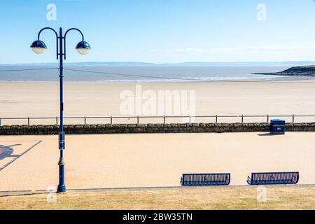 The promenade is empty and the sandy beach very quiet at Barry Island on a sunny Spring bank holiday afternoon during the 2020 coronavirus crises. Stock Photo