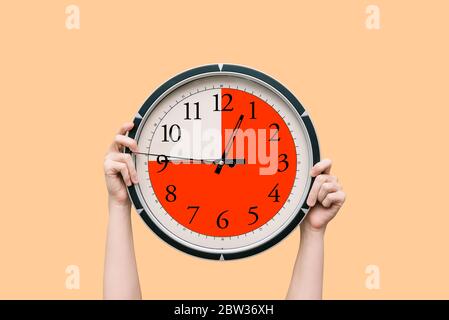 Round clock with a dial shows three-quarters of an hour. The time timer is fifteen minutes. Watch in the hands of a woman. The concept of a schedule Stock Photo