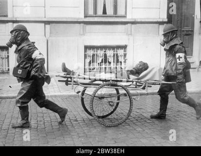 A  victim  of the brussels air raid . Gas masked ambulance men busy as bomb and gas attack is made on city . Men , women and children lay prone on the Brussels pavements when a mock aerial bomb and gas attack was made on the city to test the defences . The citizens co operated with the military authorities to make the attack as realistic as possible . Gas masked Red Cross men rushed  victims  to first aid centres , and fire fighters wearing gas masks concentrated their efforts on buildings set alight by the  bombs  . A child  victim  of the raid being rushed by gas masked Red Cross men to a fi Stock Photo