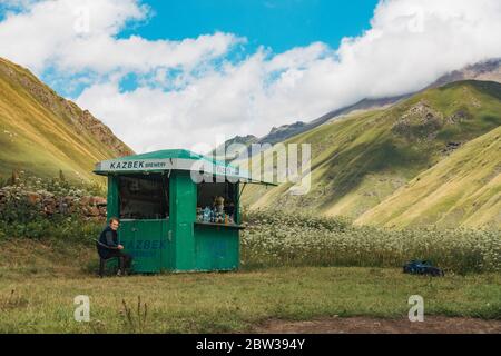 A woman tends a small food and drink kiosk in the Truso Gorge on the Terek River, Kazbegi, Georgia Stock Photo