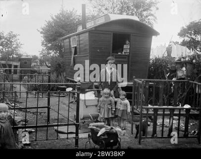 Mrs Shaw with her 3 children who live in the caravan seen behind . 25 October 1934 Stock Photo