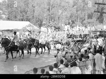 Emperor celebrates in midst of crisis anniversary of coronation . Despite the menace of the Italian invasion the anniversary of the coronation of Emperor Haile Selassie of Abyssinia was celebrated with regal pomp in Addis Ababa . The event was commemorated with a State procession through te town and a great military parade . Thousands of tribesmen led by important chieftains flocked into the capital to pay homage to their ruler and express their loyalty to him in the present crisis . Photo shows , the Emperor ' s coach in the State procession through Addis Ababa . Note the uniform of the posti Stock Photo