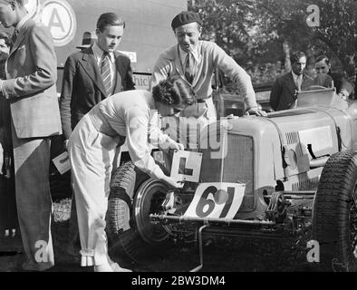 Mrs Kay Petre , the famous woman racing driver , who established a new women 's record for the Shelsley Welsh Hill Climb in her Riley with 45 and 1/5th seconds , plays a practical joke on Raymond Mays ( behind ) , whose record for the climb remained unbeaten , as she fixes a totally undeserved  Learners  plate to his ERA . Raymond Mays put up the best time of the day for the Worcester Climb with 41 seconds . 29 September 1935 Stock Photo