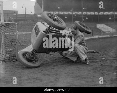 West Ham speedway to introduce midget car racing . Brooklands record holder designs new baby . Photo shows Mr G B Bush lifting his midget car with one hand to make an adjustment at West Ham watched by Harold ( Tiger ) Stevenson . 20 June 1935 Stock Photo