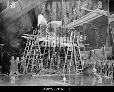 A nightime view of the day and night work to repair the damage to the ocean liner ,  Aquitania  made by rough seas . Picture shows ; Dockers at work on the  Aquitania  in the new graving dock at Southampton . 14 January 1935 Stock Photo