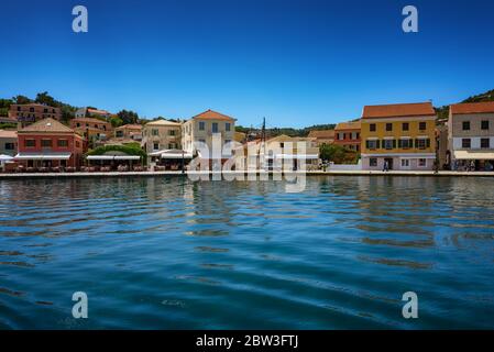 Paxos Island, Greece. View of beautiful Loggos Harbor sea bay with calm turquoise water, ships and yachts colorful old houses and blue sky with white Stock Photo