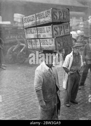 Billingsgate Fish Market is already working at top pressure to deal with the terrific demand for Good Friday fish . The approach of the Easter festival means greatly increased work for Billinsgate , which has to supply eight million Londoners . Photo shows , the busy scene at Billingsate Market . 4 April 1936 Stock Photo