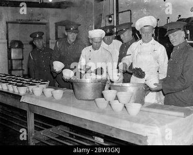 Woolwich barracks troops are making their own christmas pudding . For the first time men of the Royal Artillery at Woolwich Barracks are making their own Christmas puddings instead of buying them from outside . Six hundred men have to be catered for in the messroom and the work of preparing and mixing the puddings has already commenced . Liberal quantities of brand and stout are the most popular ingrediants . Photo shows , Cooks finding willing assistants at the Royal Artillery barracks , Woolwich , when the Christmas puddding column is drawn up on the kitchen table . 7 December 1935 Stock Photo