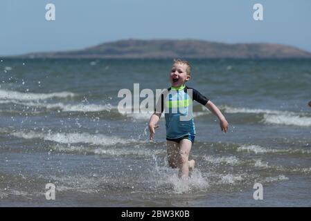 Four year old Cian Walshe plays in the sea off Portmarnock Beach, Dublin, as the warm weather continues. Stock Photo
