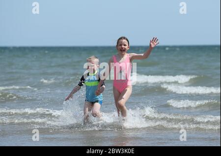 Four year old Cian Walshe and his sister Ella, eight, plays in the sea off Portmarnock Beach, Dublin, as the warm weather continues. Stock Photo