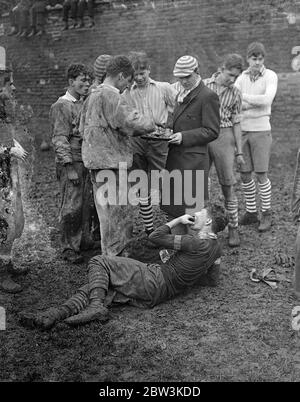 Collegues and oppidans play Eton game in mud . The annual Wall Game , the traditional struggle between Collegers and Oppdiana took place at Eton College as part of the St Andrew ' s Day celebrations . Each side worked hard to score the first goal for 26 years , but rain made play extremely difficult . Photo shows , players sucking lemons in the interval . 30 November 1935 Stock Photo