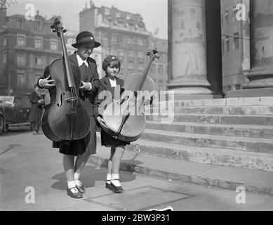 London ' s Musical Children Play At The Queen ' s Hall . Hundreds of young musicians are taking part in the School Orchestra and Junior Band Festival at Queen ' s Hall , London . Photo shows : Girl musicians arriving at the Queen ' s Hall with their cellos . 16 May 1936 Stock Photo