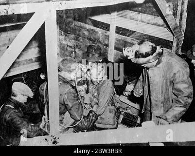 Entomed men rescued after ten days in abandoned mine . These are the first original pictures to reach London of the rescue of the two men Dr D E Robertson , 62 year old Toronto physicisan , and Charles Alfred Scodding , who were entomed for ten days in an abandoned gold mine at Moone River , Nova Scotia . Volunteer crews worked night and day to break down the rock barrier that cut off the trapped men , who were kept alive only by food poured down a drill driven through the rock and by flood water that threatened their lives . When reached the men were lying on a ledge only a few inches above t Stock Photo