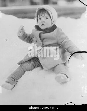Quin ' s snow problem . Annette Dionne , one of the famous Quintuplets , wrestles with the problem of making snowballs with her hands pinned in her sleeves at Callender , Ontario . 19 April 1936 Stock Photo