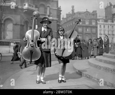 London ' s Musical Children Play At The Queen ' s Hall . Hundreds of young musicians are taking part in the School Orchestra and Junior Band Festival at Queen ' s Hall , London . Photo shows : Girl musicians arriving at the Queen ' s Hall with their cellos . 16 May 1936 Stock Photo