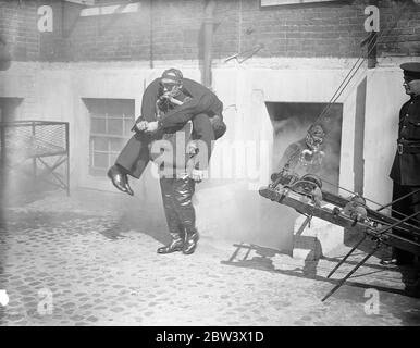 London Fireman Give Rescue Display . A display of rescue work , fire fighting and drill was given by members of the London Fire Brigade at the Brigade ' s Headquarters , Southwark . Photo shows : Firemen wearing the latest type respirators making a rescue through dense smoke . 26 Aug 1936 Original caption from negative Stock Photo