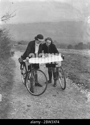 Photo shows: girl cyclists reading maps. Girls who spent their holiday a-wheel admiring the magnificent view at Newlands Corner, the famous Surrey beauty spot between Dorking and Guildford. 28 March 1937 Stock Photo