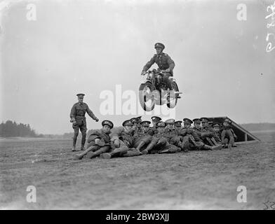 The London Divisional Signals (City of London Signals), Territorials, rehearse the display of trick motorcycle riding at Mons Barracks, Aldershot, in preparation for the Royal Tournament, which opens at Olympia on May 27. Photo shows one of the trick riders flying over his comrades who are sitting on the ground 27th March 1937 Stock Photo