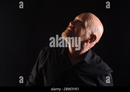 portrait of a man in low key, smiling and look to up Stock Photo