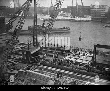 Demolition and construction at London Bridge . Demolition and construction work being carried on side-by-side in the shadow of London Bridge . The wharfage of the pool of London is being extended by an addition to Fresh Wharf and an old warehouse is being demolished to make way for a great new building . Photo shows, extending the wharfage Fresh Wharf , lower Thames Street , London Bridge . 19 September 1936 Stock Photo