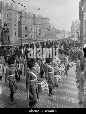 Now that the King and Queen have taken up residence at Windsor Castle a full guard is being mounted for the first time since King George V last days there. Photo shows: The guard, headed by the band, marching away from Windsor Castle after the guard change. 9 April 1937 Stock Photo