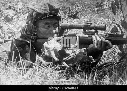 The other side of the picture - sniper on summer exercise. Photo shows: sprawled among the summer grasses his head covered with a concealing cloth, a sniper of the Kazakh Red Army peers through his telescopic sights from his nest during the summer exercises of the Red Army in Kazakhstan. The Kazakh Soviet Socialist Republic is located in Soviet Central Asia, between the Caspian Sea, Western Siberia and the frontier of Western China. 24 April 1937 [?] Stock Photo