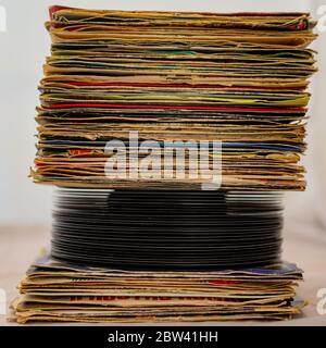 stack of 45 rpm vinyl records arranged in a vertical stack. The discs have covers used in poor condition for wear Stock Photo