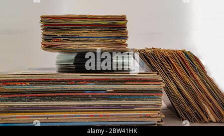 stack of 45 and 33 rpm vinyl records arranged in a vertical stack. The discs have covers used in poor condition for wear Stock Photo