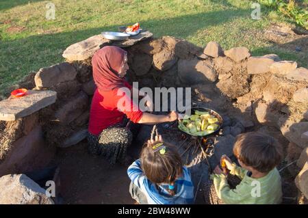 Asien, Türkei, Provinz Bingöl, Frau vom Stamm der Beritan-Nomaden an  Feuerstelle beim Zubereiten von Essen auf einer Hochweide in den Serafettin-Berg Stock Photo