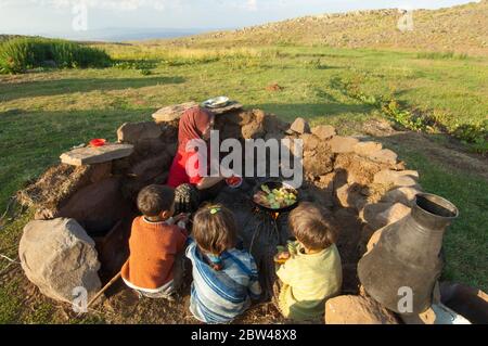 Asien, Türkei, Provinz Bingöl, Frau vom Stamm der Beritan-Nomaden an  Feuerstelle beim Zubereiten von Essen auf einer Hochweide in den Serafettin-Berg Stock Photo