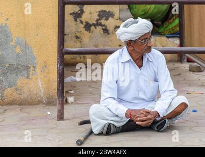 Somnath,  Gujarat, India - December 2018: Portrait of an old man with spectacles, dressed in traditional white clothing, sitting on the floor. Stock Photo