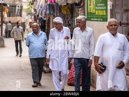 Somnath, Gujarat, India - December 2018:  Two elderly Indian men walking in an alley in the old town and having a conversation. Stock Photo