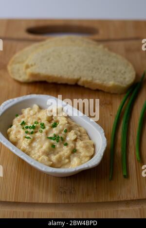 German Bavarian beer garden cheese spread made with Camembert, butter, beer, paprika and scallions on wooden background with homemade sourdough bread Stock Photo