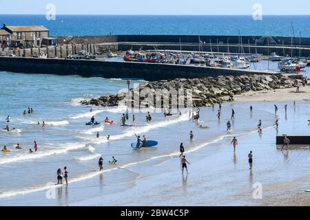 Lyme Regis, Dorset, UK.  29th May 2020.  UK Weather.  The beach at the seaside resort of Lyme Regis in Dorset is busy with families and sunbathers paddling in the sea to cool off in the scorching hot sunshine during the afternoon.  Picture Credit: Graham Hunt/Alamy Live News Stock Photo