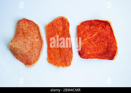 Dried slices of pork, beef of different shapes with spices on a white background. Crispy meat chips. Tasty appetizer. View from above Stock Photo