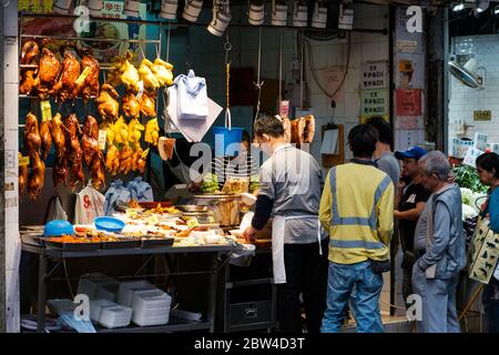 Hong Kong - November, 2019: People buying roasted ducks, peking duck and roast goose, on street food market in Hong Kong Stock Photo