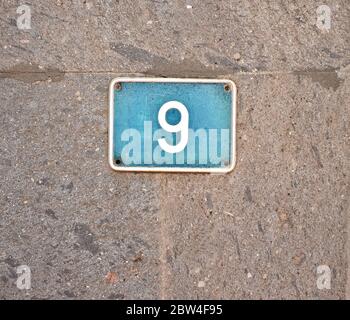 9, nine - light blue plate on gray stone surface. Stock Photo