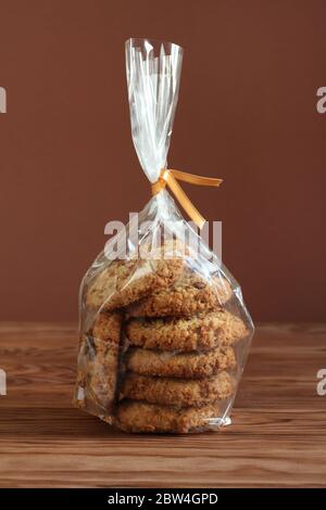 Oatmeal cookies with walnuts and raisins in a transparent bag on a wooden table Stock Photo