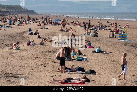 Portobello, Scotland, UK. 29 May 2020. Sunshine and temperatures of 23C at Portobello beach and promenade brought crowds of people outdoors. The relaxed covid-19 lockdown rules announced by the Scottish Government yesterday allows the public to sunbathe.  Iain Masterton/Alamy Live News Stock Photo