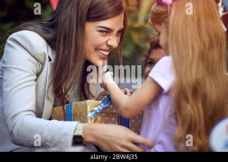 Smiling mother opening birthday gift with her cute child girl. Stock Photo