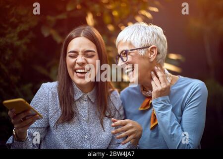Happy daughter and her smiling senior mother have fun together outdoor at home. Stock Photo